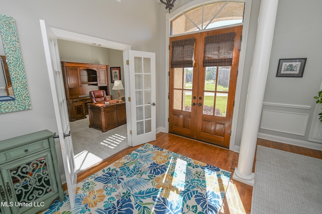 foyer entrance with light hardwood / wood-style floors, french doors, and decorative columns