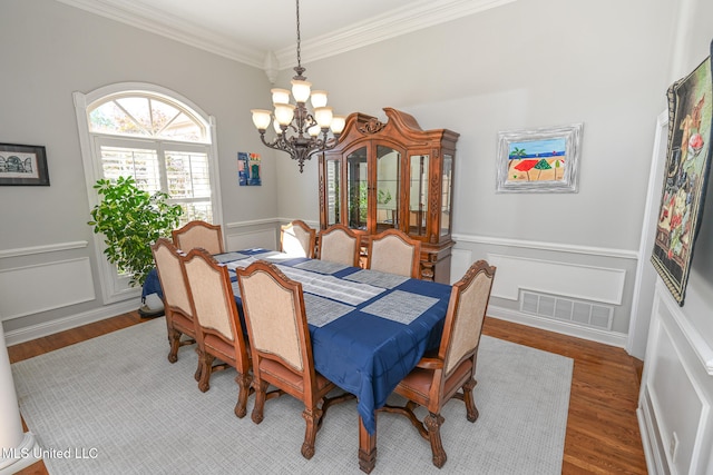 dining space with wood-type flooring, a notable chandelier, and ornamental molding