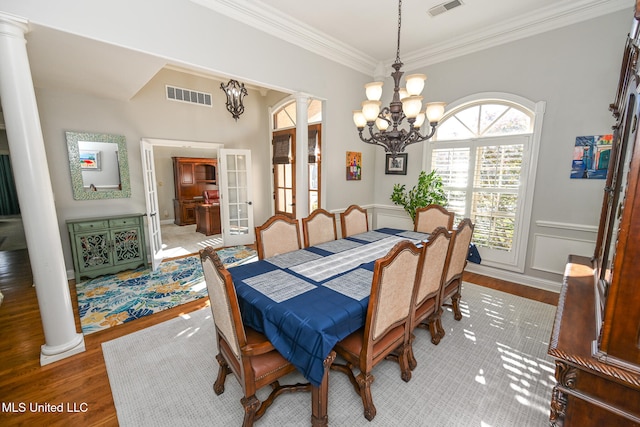 dining area with hardwood / wood-style flooring, french doors, ornate columns, and crown molding