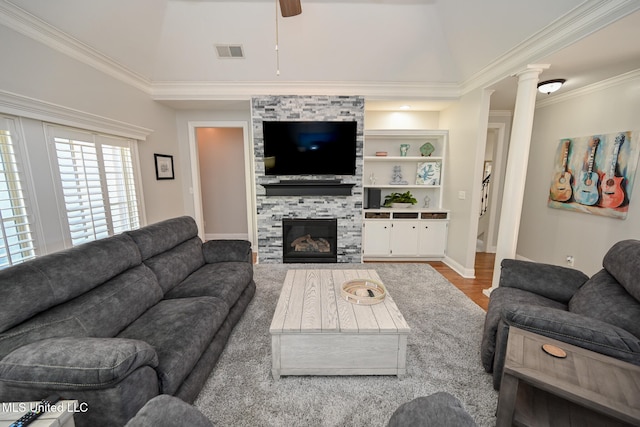 living room with wood-type flooring, decorative columns, ceiling fan, crown molding, and a fireplace