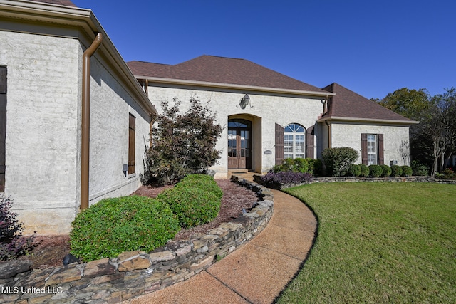 french country inspired facade featuring french doors and a front lawn