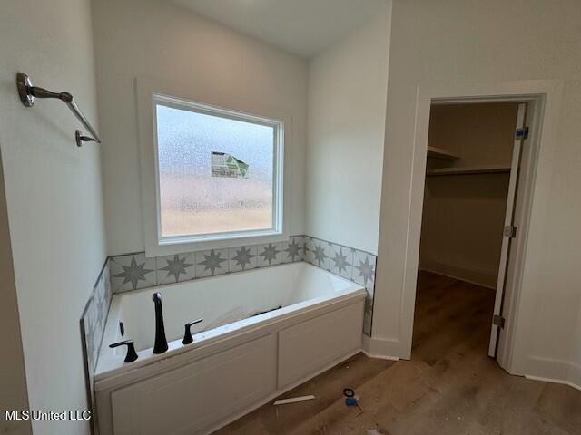 bathroom with a washtub and hardwood / wood-style floors