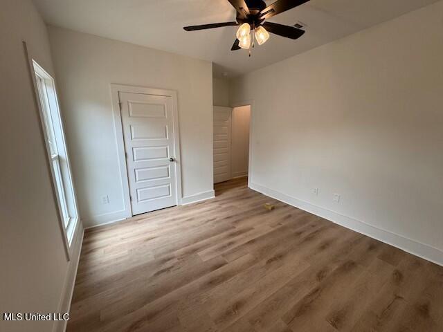 unfurnished bedroom with ceiling fan and wood-type flooring