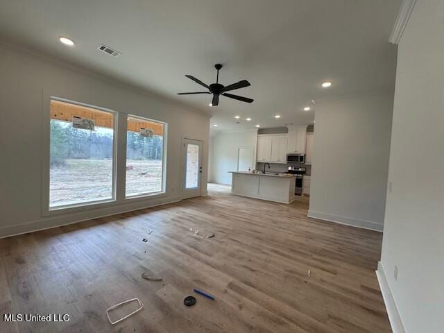 unfurnished living room with ornamental molding, ceiling fan, and wood-type flooring