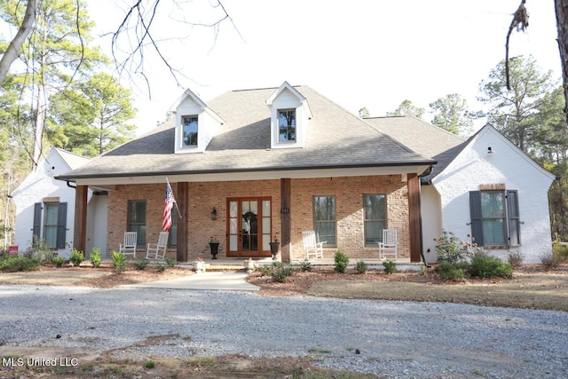 view of front facade featuring brick siding, a porch, and a shingled roof