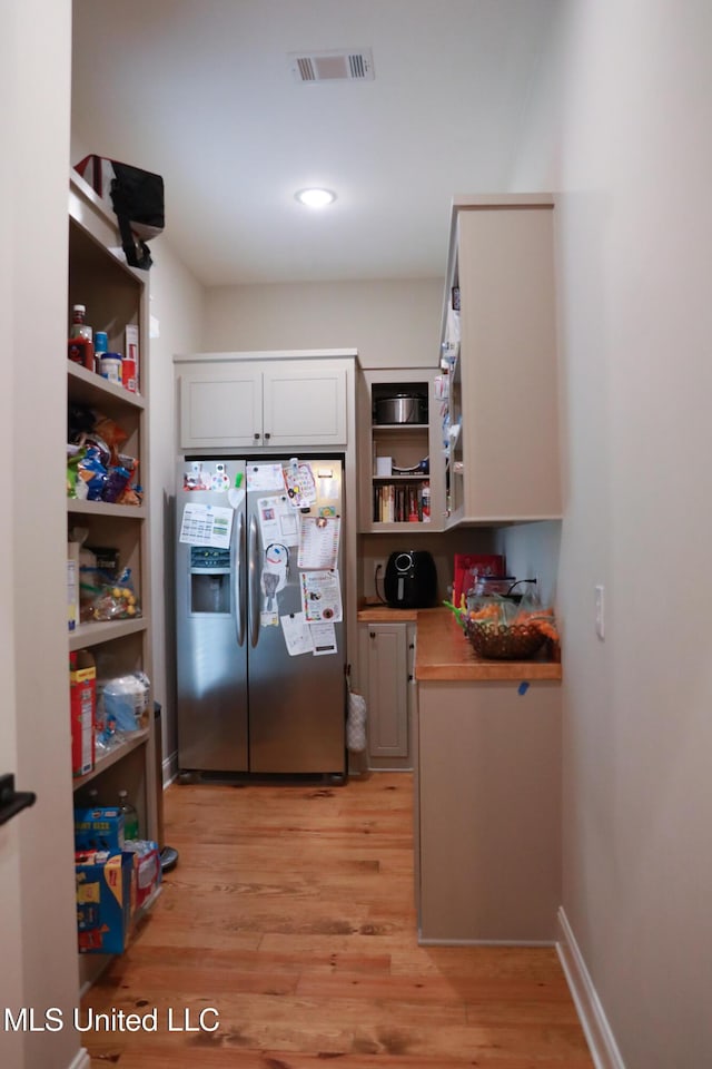 kitchen with visible vents, open shelves, light wood-style flooring, light countertops, and stainless steel fridge