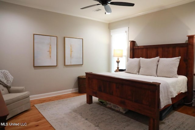 bedroom featuring baseboards, wood finished floors, a ceiling fan, and crown molding