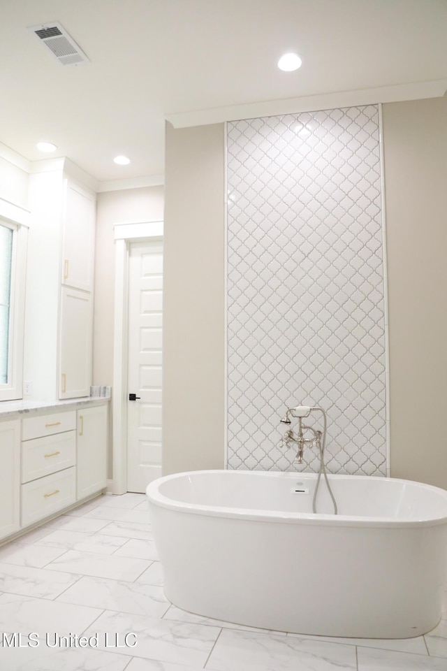 bathroom with a freestanding tub, recessed lighting, visible vents, and marble finish floor