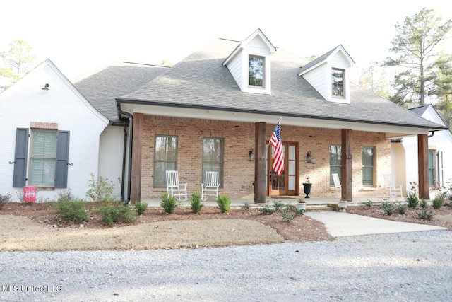 view of front of home with brick siding, covered porch, and a shingled roof