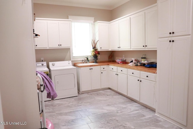 clothes washing area with cabinet space, washer and dryer, and a sink