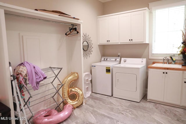 laundry area featuring washing machine and dryer, cabinet space, marble finish floor, and a sink