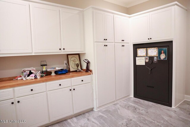 kitchen featuring marble finish floor, light countertops, and white cabinetry