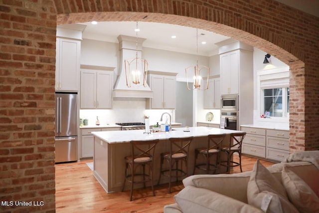 kitchen with premium range hood, open floor plan, a breakfast bar area, light countertops, and stainless steel appliances