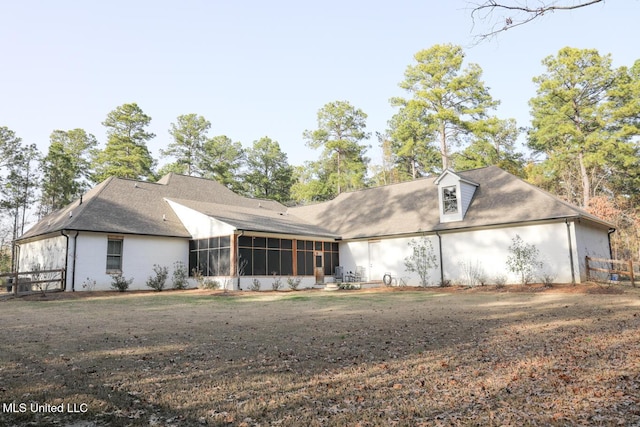 rear view of house featuring a lawn, a sunroom, and roof with shingles