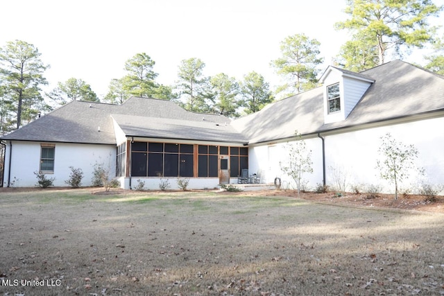 rear view of house with a yard, a sunroom, and roof with shingles