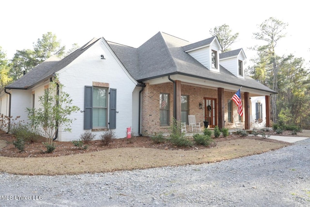 view of front of house featuring brick siding, covered porch, and a shingled roof