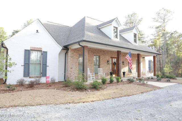 view of front of house featuring a porch, brick siding, and a shingled roof