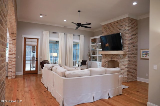 living area with baseboards, a ceiling fan, light wood-type flooring, and ornamental molding