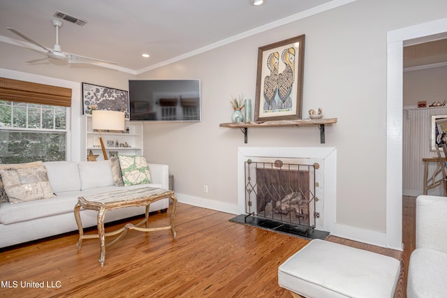 319 Washington Ave, Ocean Springs, MS 39564 - living area with ornamental molding, a ceiling fan, wood finished floors, baseboards, and a fireplace with raised hearth