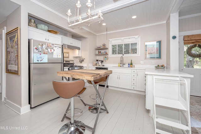 319 Washington Ave, Ocean Springs, MS 39564 - kitchen with freestanding refrigerator, stove, under cabinet range hood, a sink, and white cabinetry