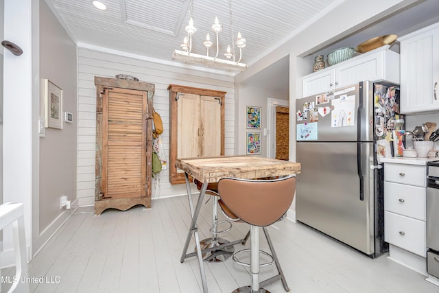 319 Washington Ave, Ocean Springs, MS 39564 - kitchen with freestanding refrigerator, white cabinetry, light wood finished floors, light countertops, and baseboards