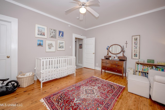319 Washington Ave, Ocean Springs, MS 39564 - bedroom with crown molding, wood finished floors, a crib, and a ceiling fan