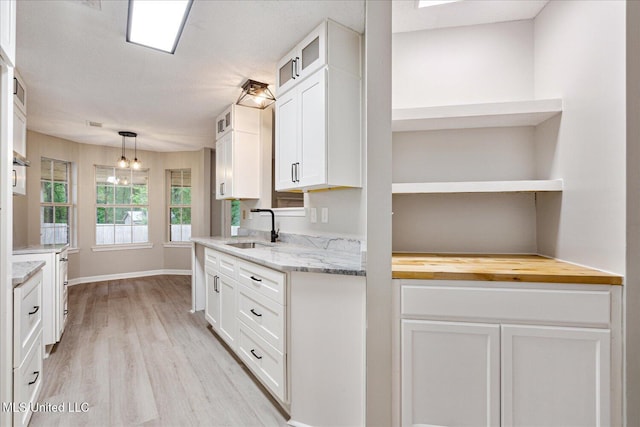 119 Vance Cv, Byhalia, MS 38611 - kitchen featuring a sink, open shelves, white cabinets, light wood-type flooring, and glass insert cabinets