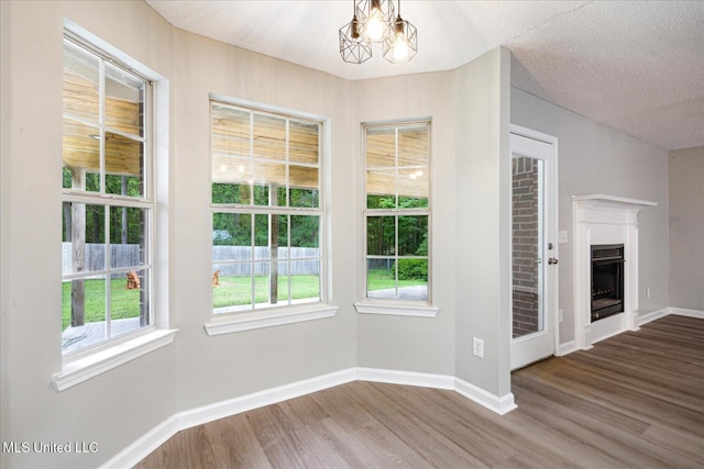119 Vance Cv, Byhalia, MS 38611 - unfurnished dining area with wood finished floors, healthy amount of natural light, baseboards, a fireplace, and a textured ceiling