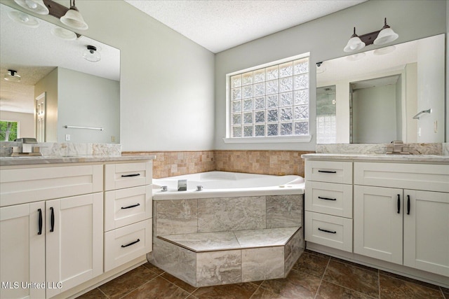119 Vance Cv, Byhalia, MS 38611 - bathroom featuring two vanities, a textured ceiling, and a garden tub