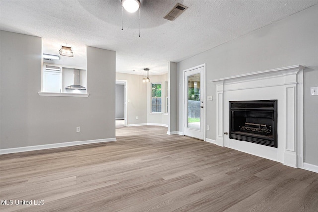 119 Vance Cv, Byhalia, MS 38611 - unfurnished living room with a ceiling fan, light wood-style flooring, a fireplace, a textured ceiling, and baseboards