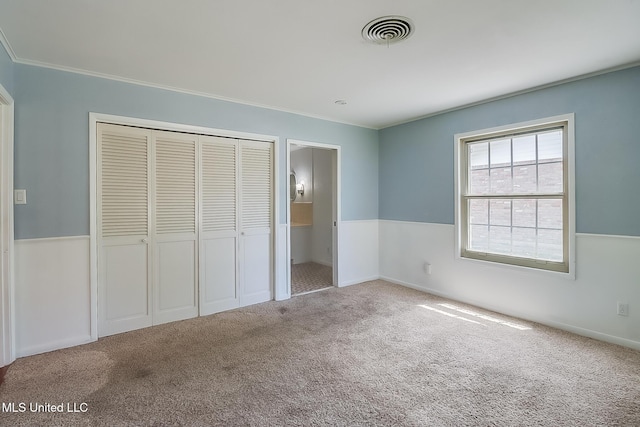 unfurnished bedroom with crown molding, a closet, and carpet floors