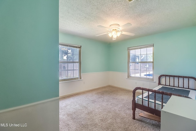 carpeted bedroom featuring ceiling fan and a textured ceiling