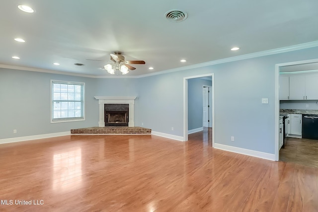 unfurnished living room featuring a fireplace, ceiling fan, light wood-type flooring, and ornamental molding