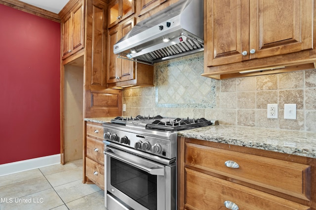 kitchen with tasteful backsplash, light tile patterned floors, extractor fan, high end stainless steel range oven, and light stone countertops