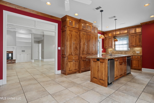 kitchen with crown molding, sink, an island with sink, hanging light fixtures, and light stone counters