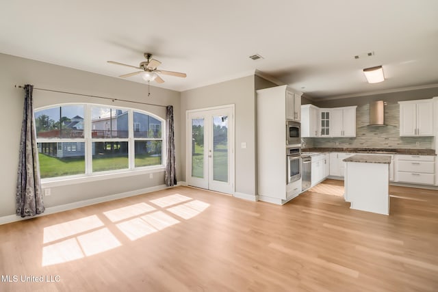 103 Buena Vista Dr, Long Beach, MS 39560 - kitchen featuring appliances with stainless steel finishes, wall chimney range hood, light wood finished floors, tasteful backsplash, and ceiling fan