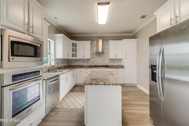 103 Buena Vista Dr, Long Beach, MS 39560 - kitchen featuring stainless steel appliances, wall chimney range hood, ornamental molding, a kitchen island, and light stone counters