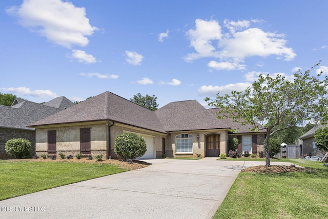 221 Penny Ln, Brandon, MS 39042 - french country home with brick siding, roof with shingles, concrete driveway, an attached garage, and a front lawn