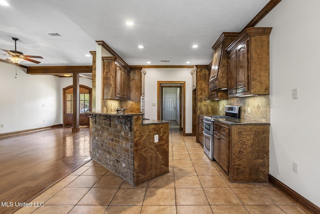 221 Penny Ln, Brandon, MS 39042 - kitchen featuring range with two ovens, decorative backsplash, a ceiling fan, a peninsula, and a kitchen bar