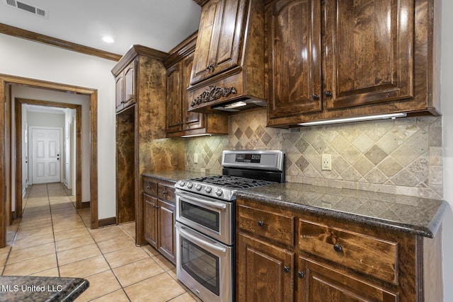 221 Penny Ln, Brandon, MS 39042 - kitchen featuring double oven range, light tile patterned flooring, dark countertops, backsplash, and ornamental molding