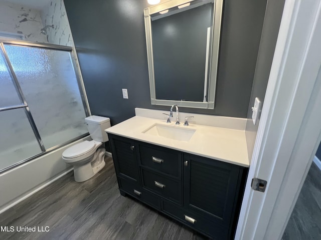 full bathroom with hardwood / wood-style flooring, vanity, toilet, and enclosed tub / shower combo