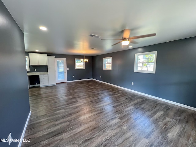 unfurnished living room featuring dark hardwood / wood-style flooring and ceiling fan with notable chandelier