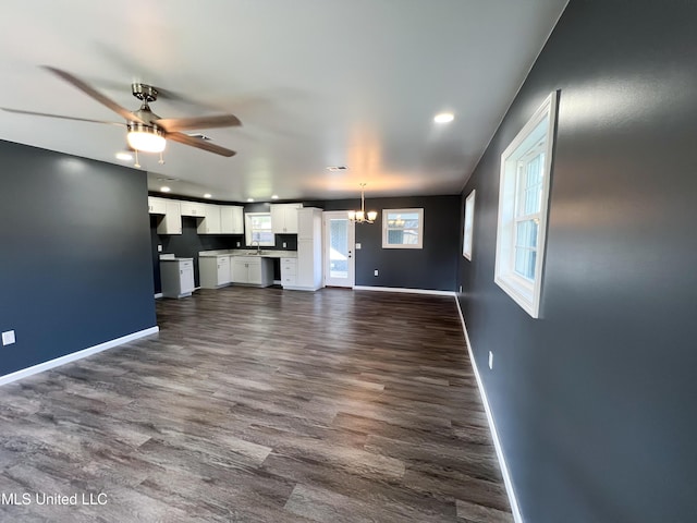 unfurnished living room with ceiling fan with notable chandelier and dark hardwood / wood-style floors