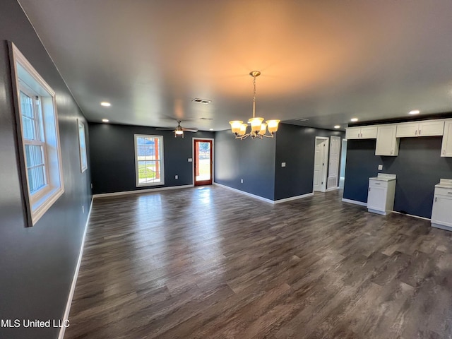 unfurnished living room featuring ceiling fan with notable chandelier and dark hardwood / wood-style floors