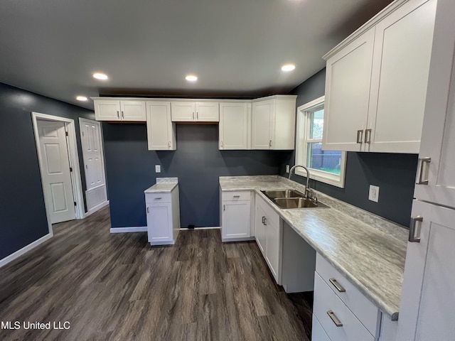 kitchen with white cabinetry, sink, light stone countertops, and dark hardwood / wood-style floors