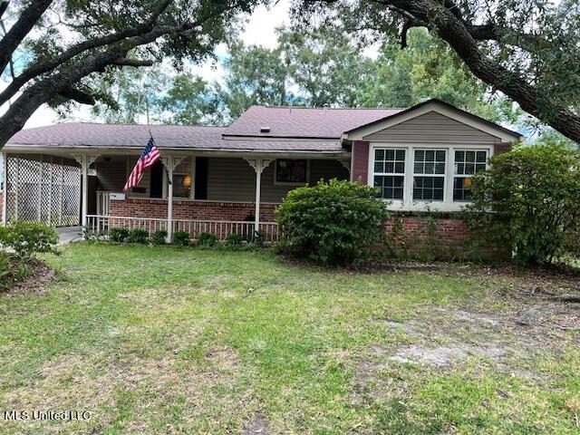 ranch-style house with a front yard and covered porch