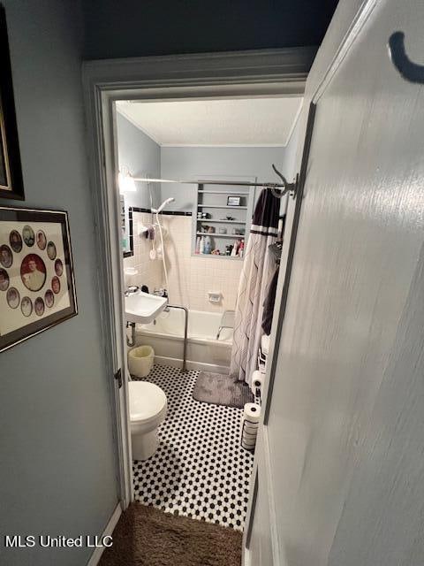 full bathroom with toilet, tile patterned floors, shower / bath combo with shower curtain, and sink