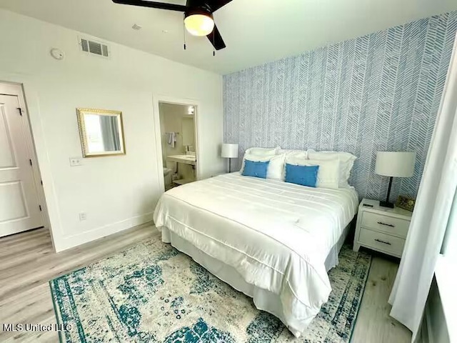 bedroom with ceiling fan, light wood-type flooring, and ensuite bath