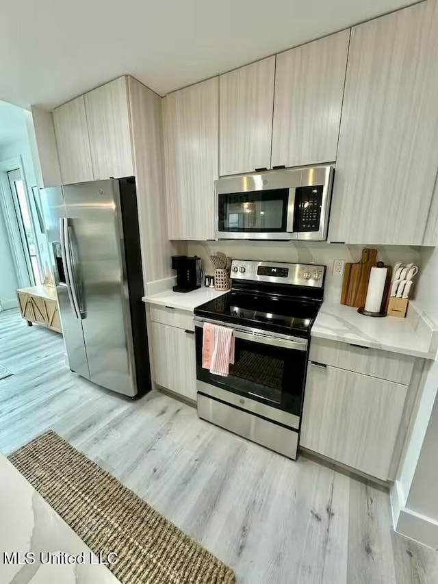 kitchen with stainless steel appliances, light brown cabinetry, and light wood-type flooring