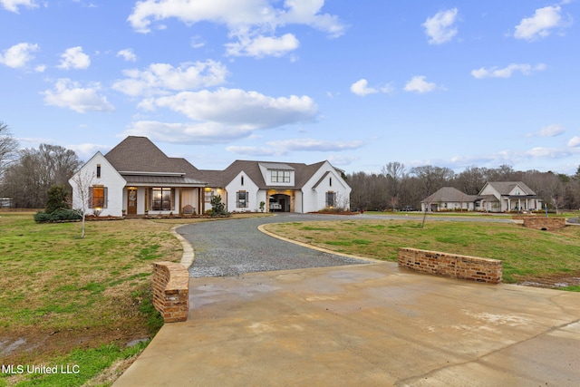 view of front of house featuring driveway, a standing seam roof, metal roof, and a front yard